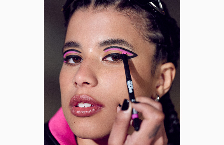 imagem de uma mulher contornando seu delineado com o Delineador Retrátil Faces na cor Pink Trend.